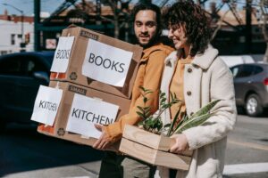 Couple carrying moving boxes and a plant