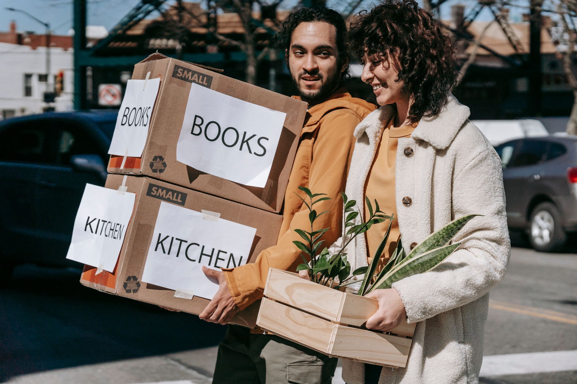 Couple carrying moving boxes and a plant