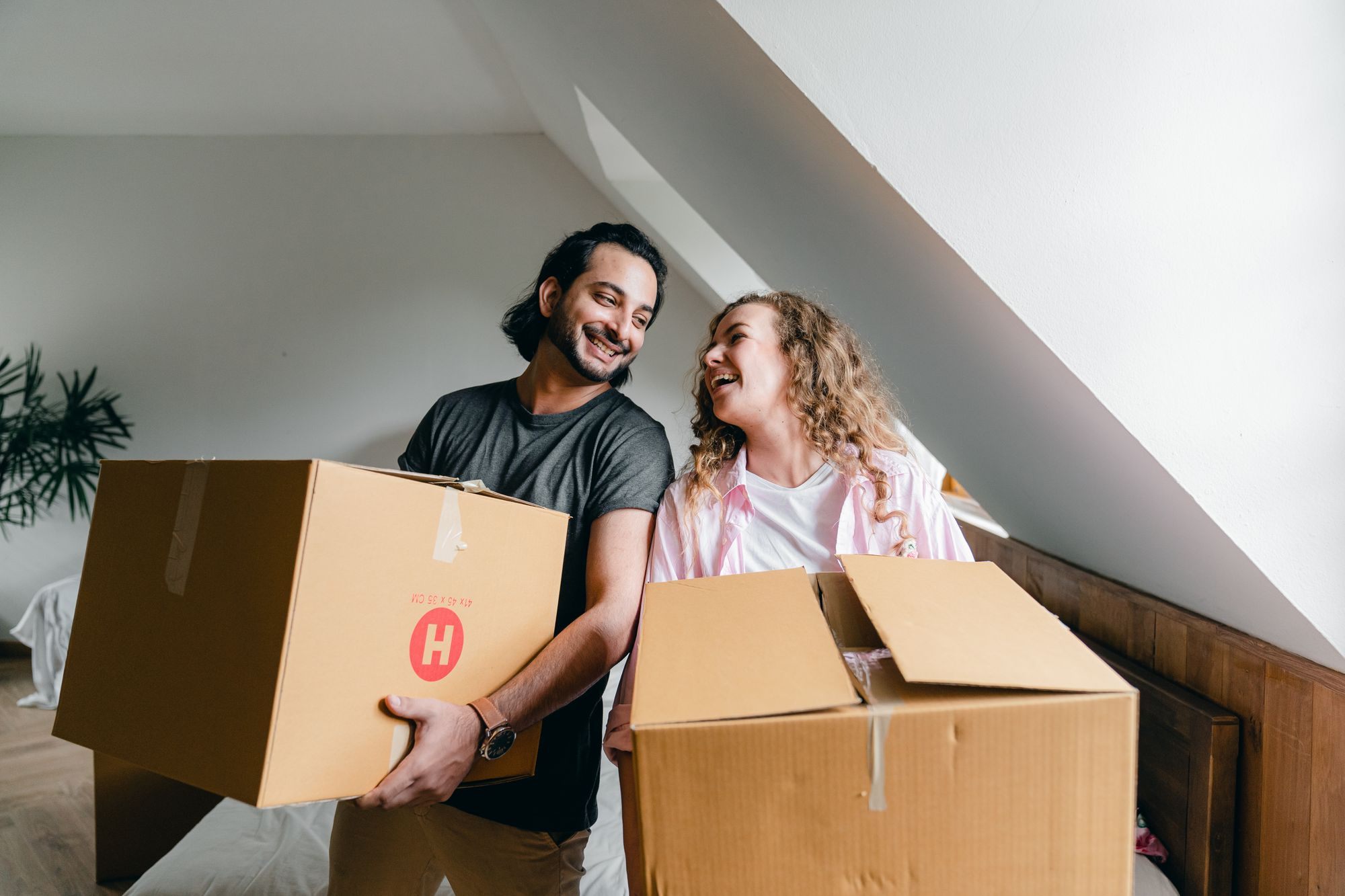 Young couple laughing while unpacking boxes in their first home