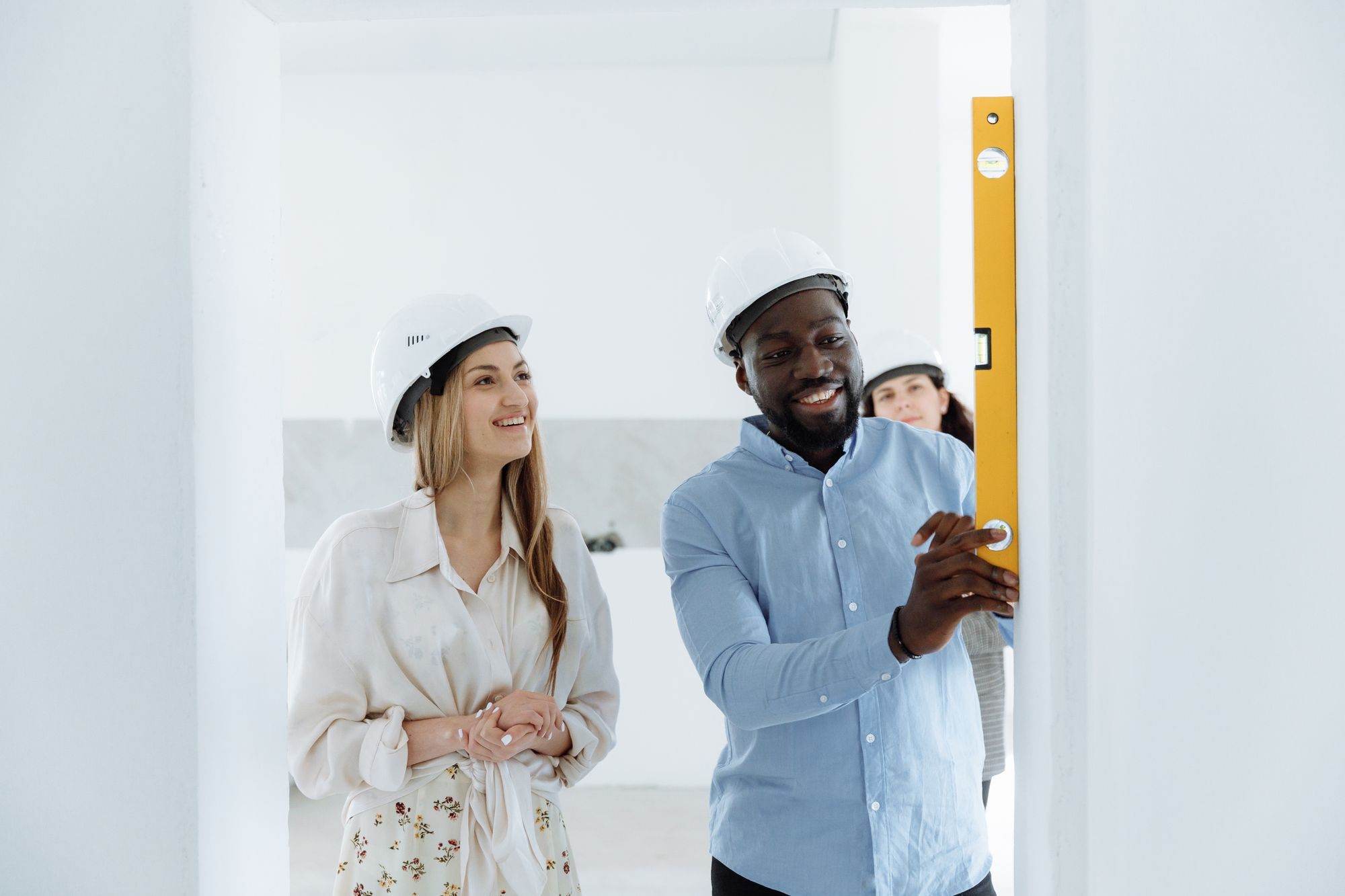 Couple in hard hats planning a renovation in an empty room