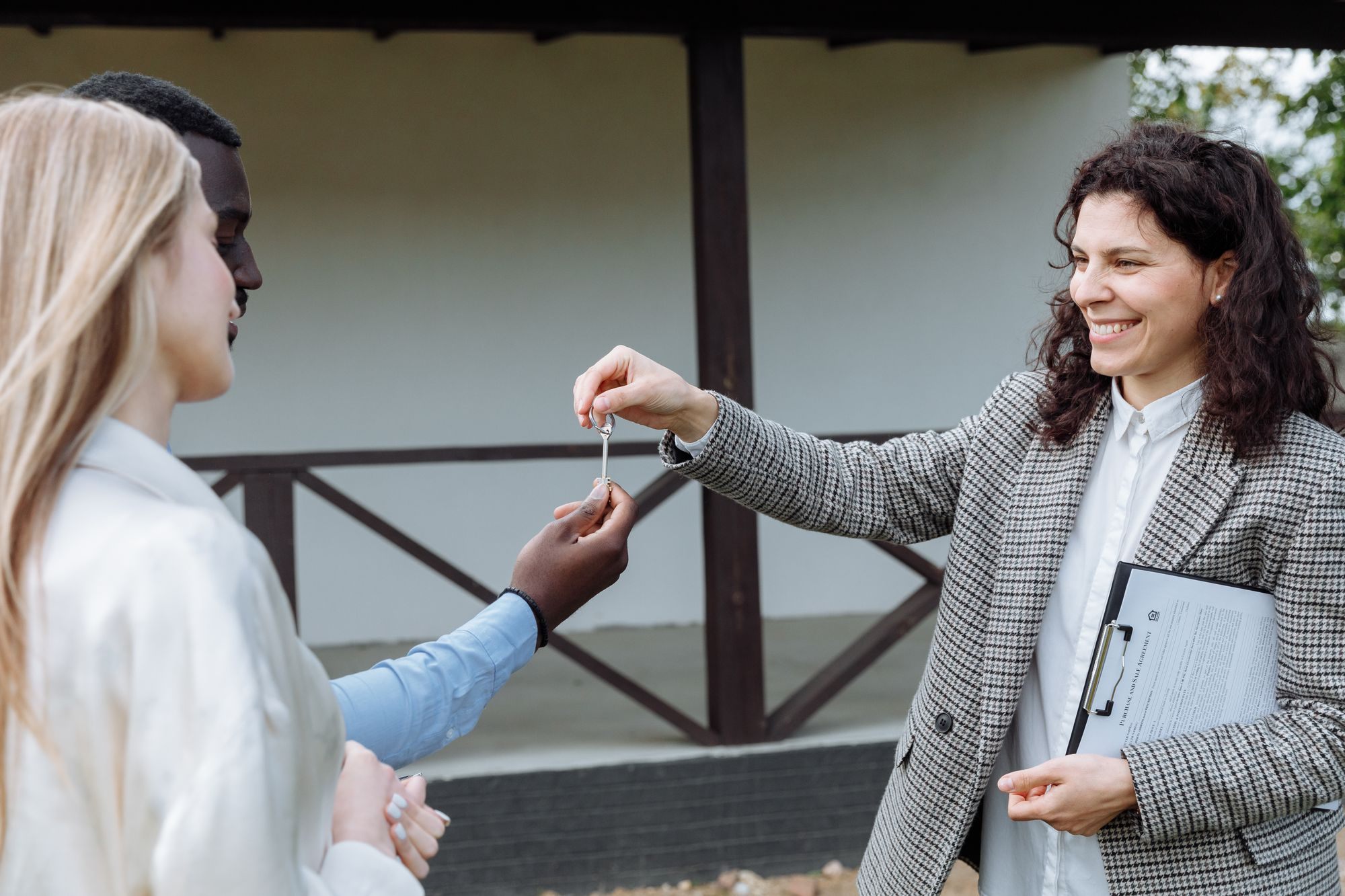 Agent handing a couple the keys on their new porch