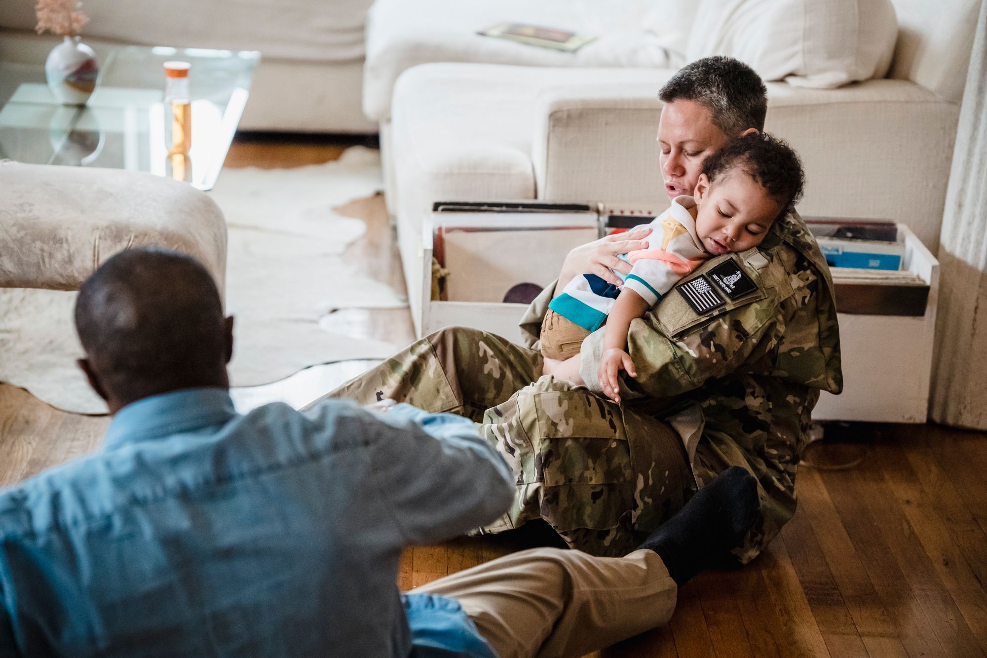 Service member in uniform hugging their child at home