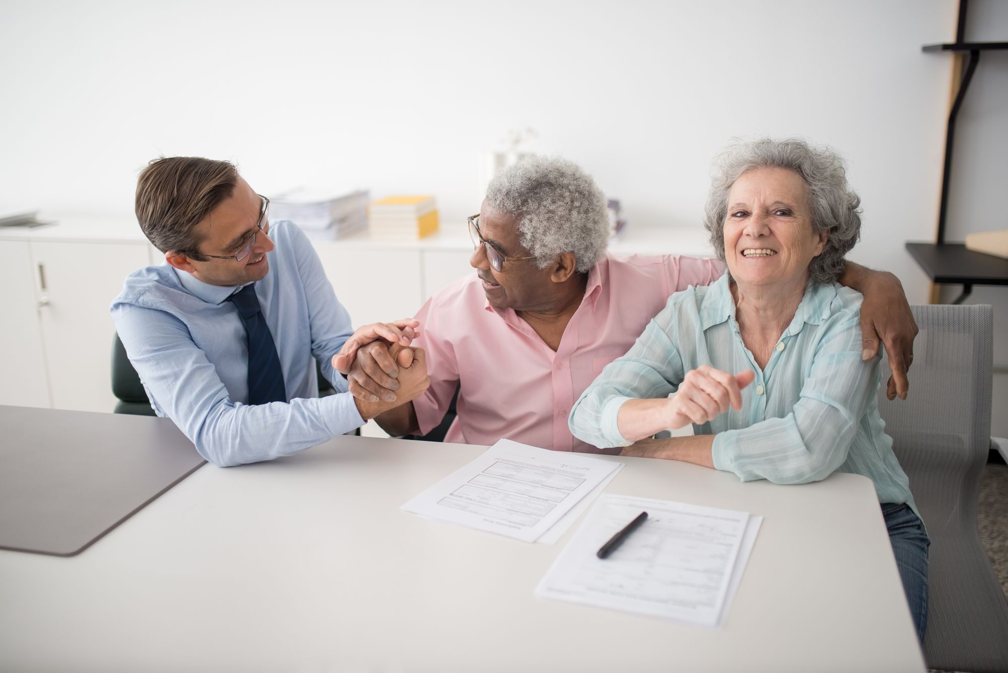 Advisor shaking hands with a couple across a desk