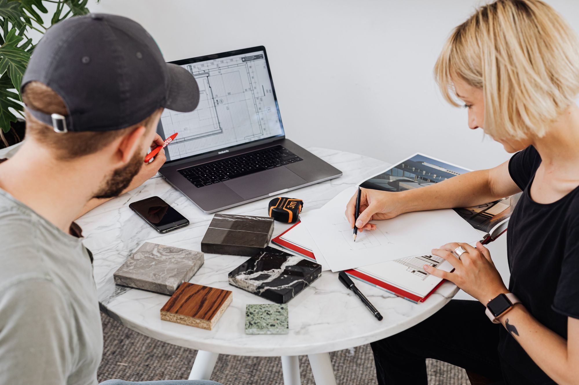 Couple at a table with a laptop, plans and material samples for a renovation