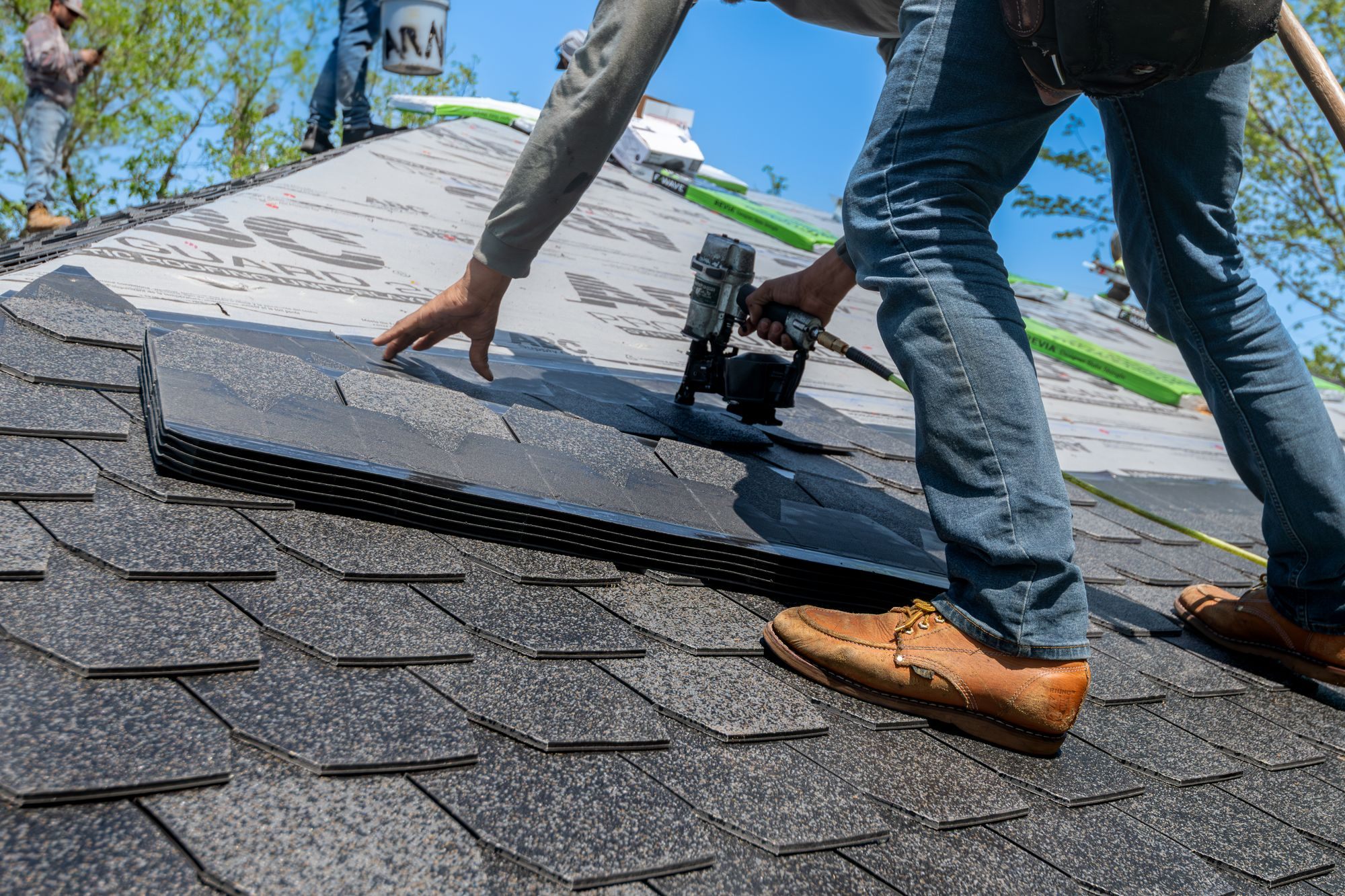 Roofer installing new asphalt shingles on a house