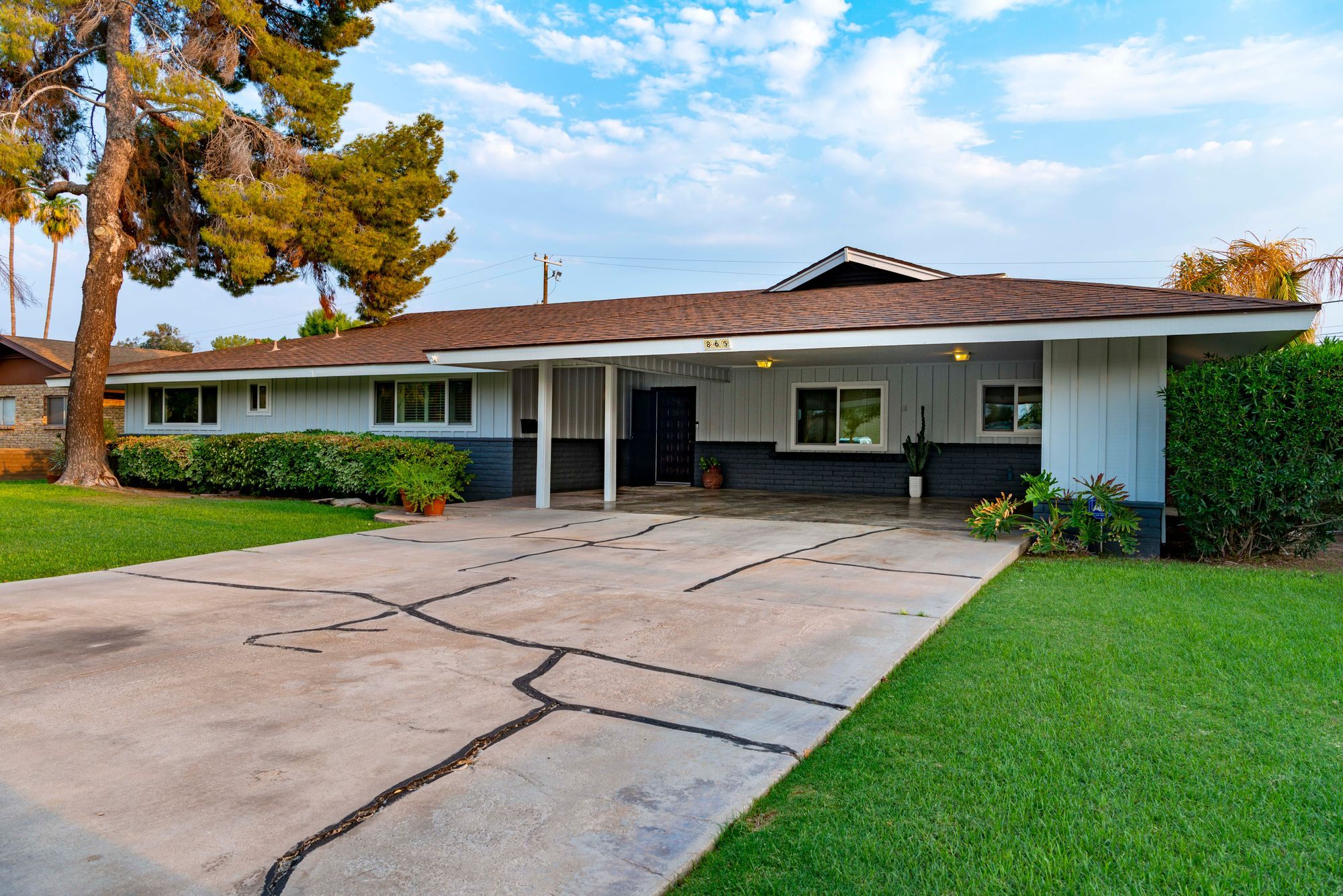 Single-storey home with a wide driveway under a sunny sky