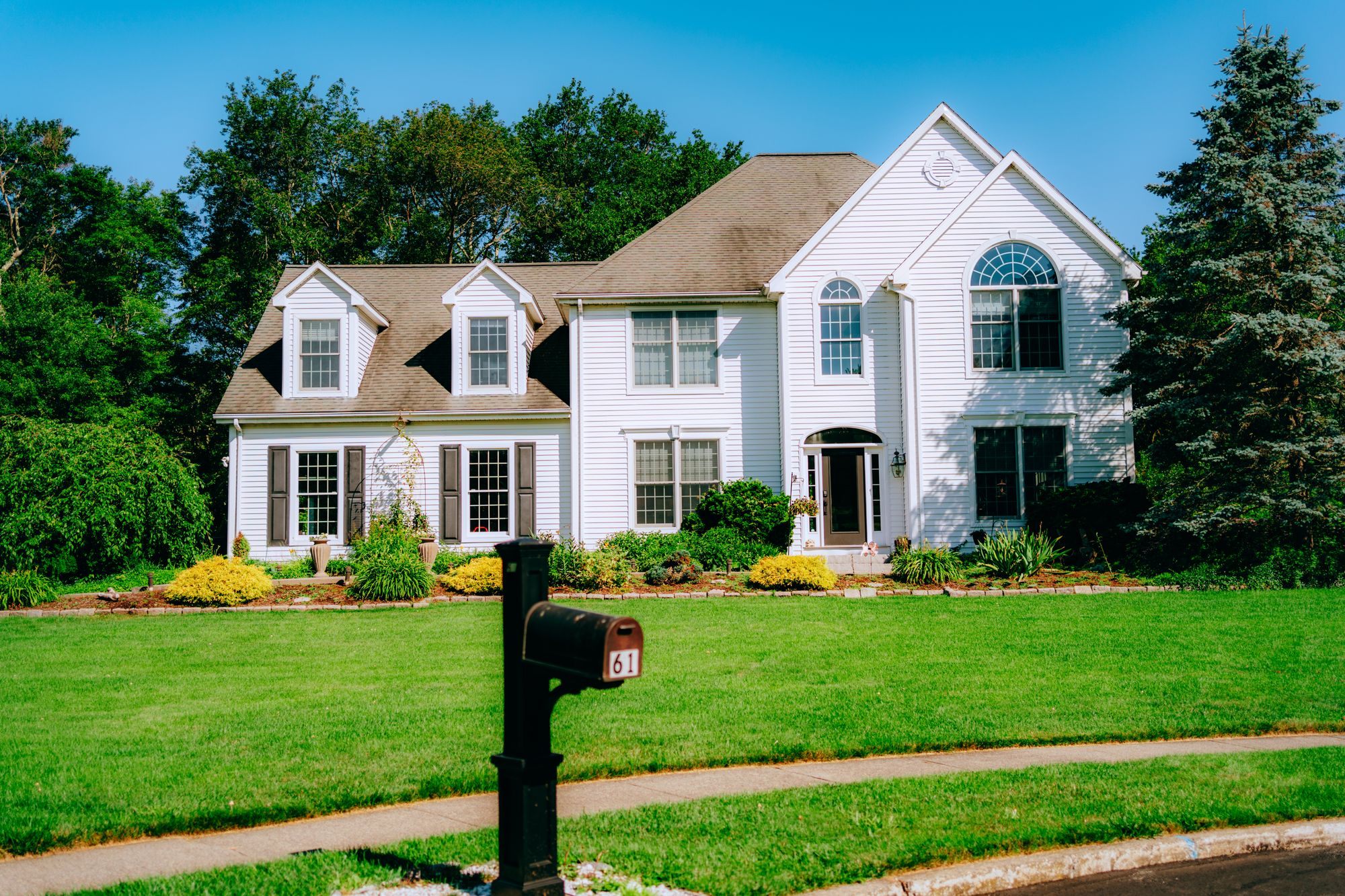 White two-story home with a manicured lawn and mailbox