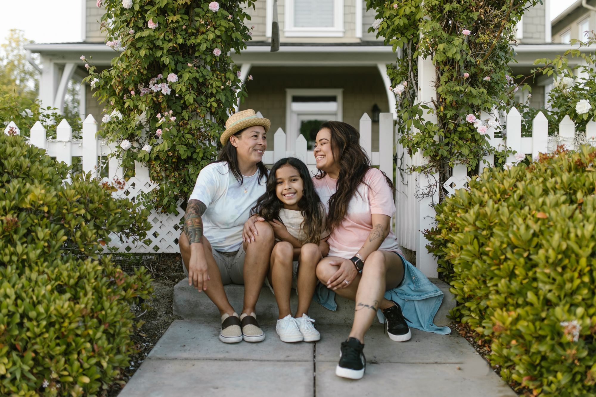 Family on the front steps of a bungalow with a white picket fence