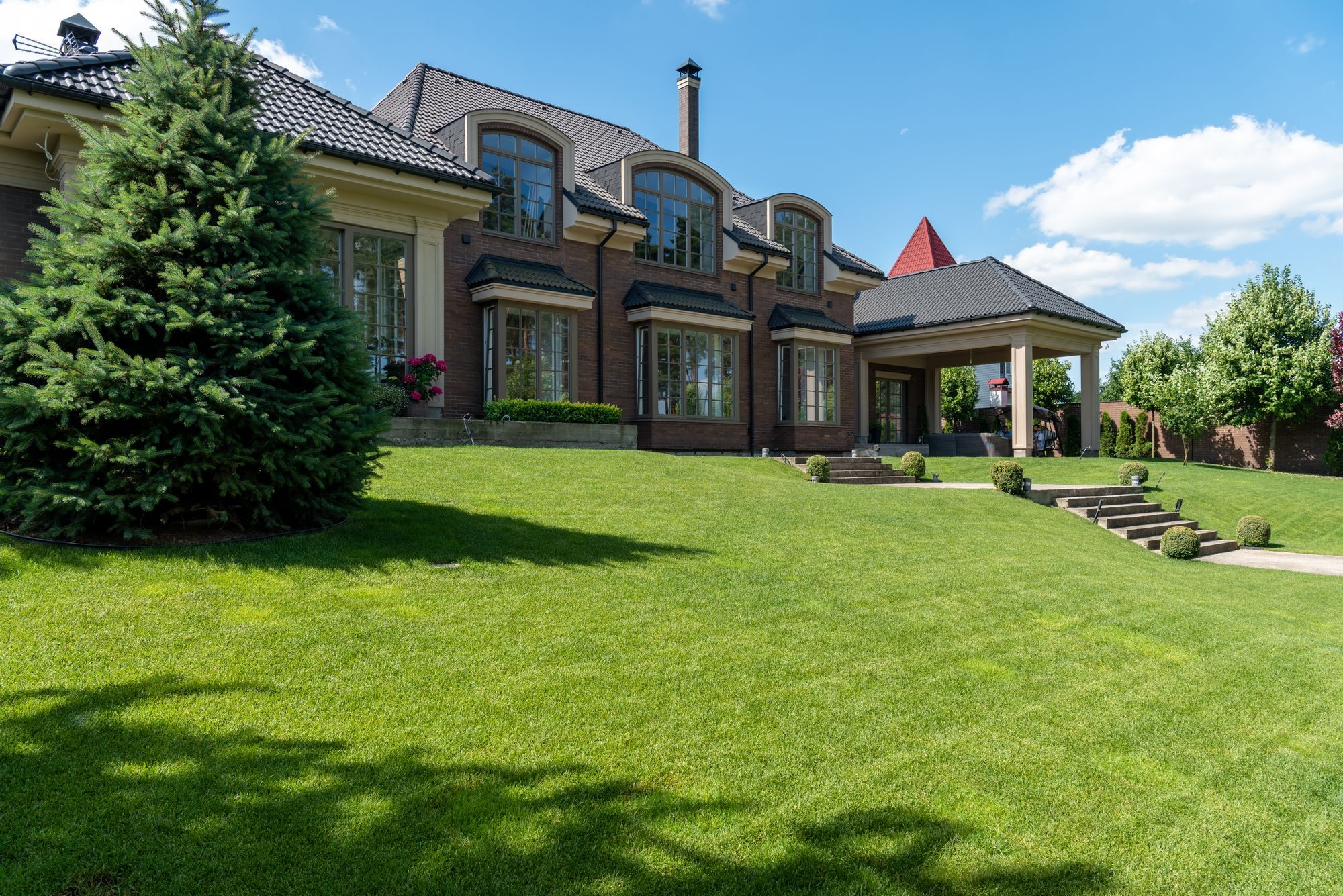 Large brick estate home with a landscaped lawn