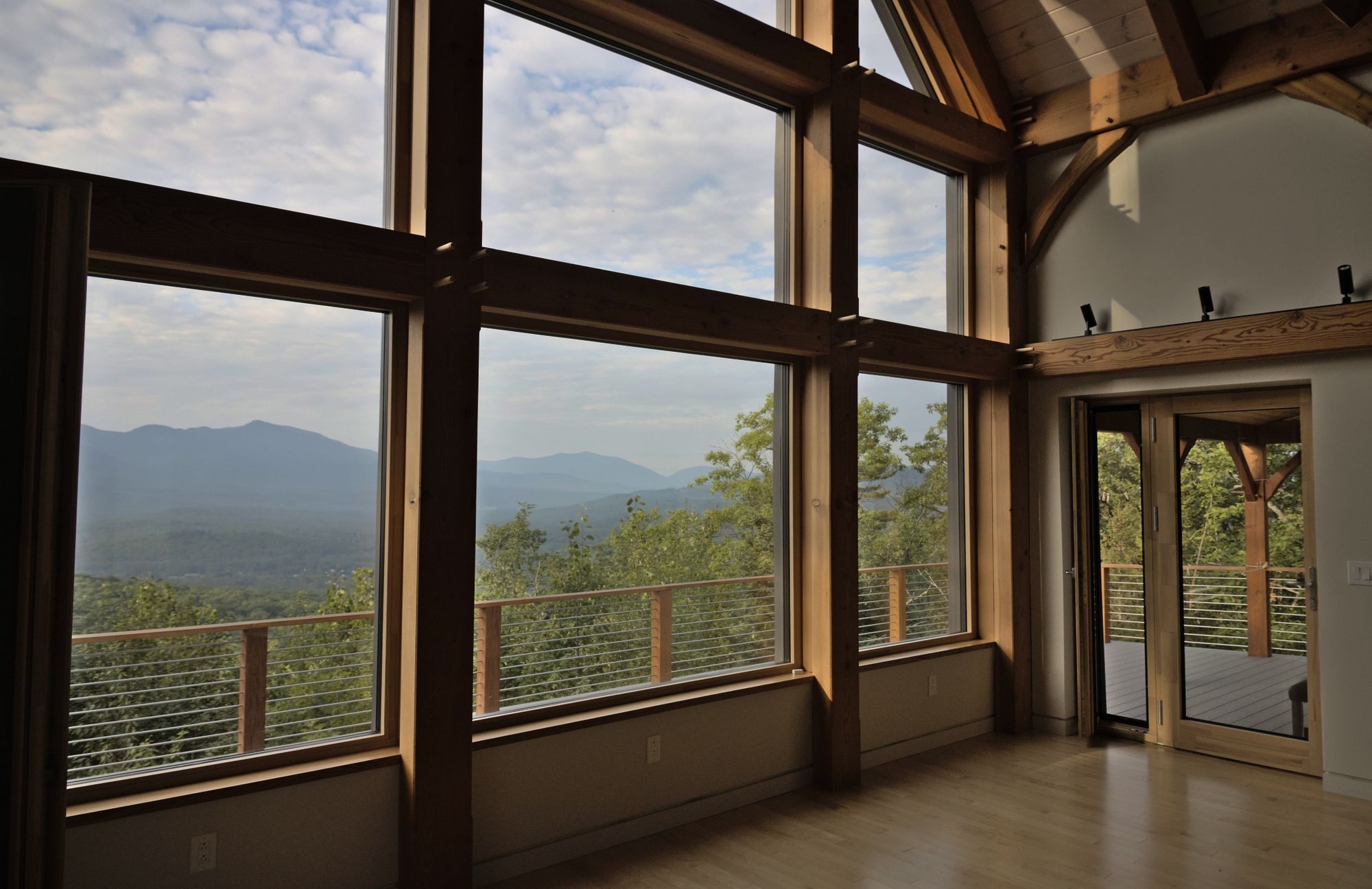 Timber-framed great room with tall windows and a mountain view