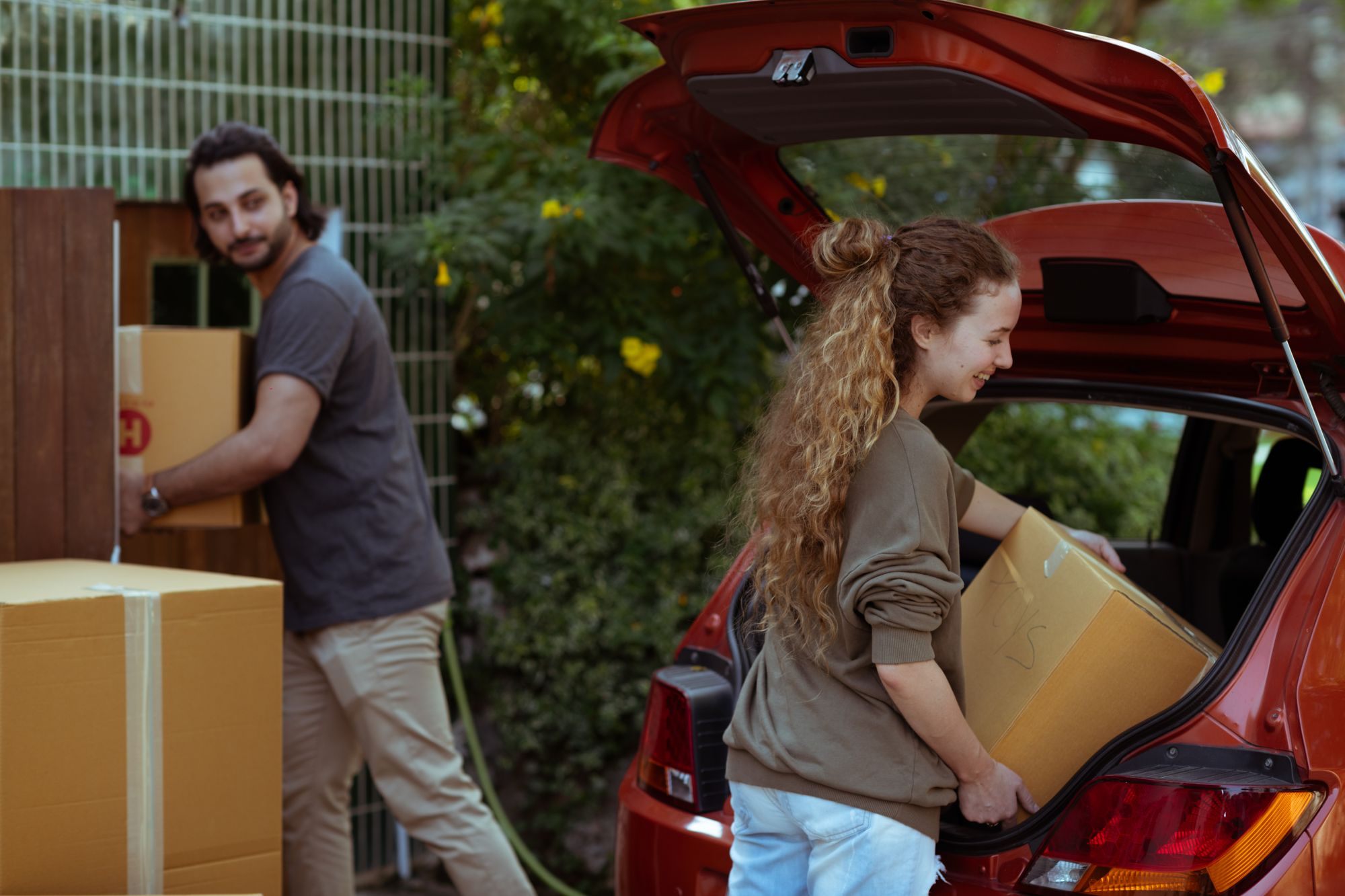 Couple unloading moving boxes from a car
