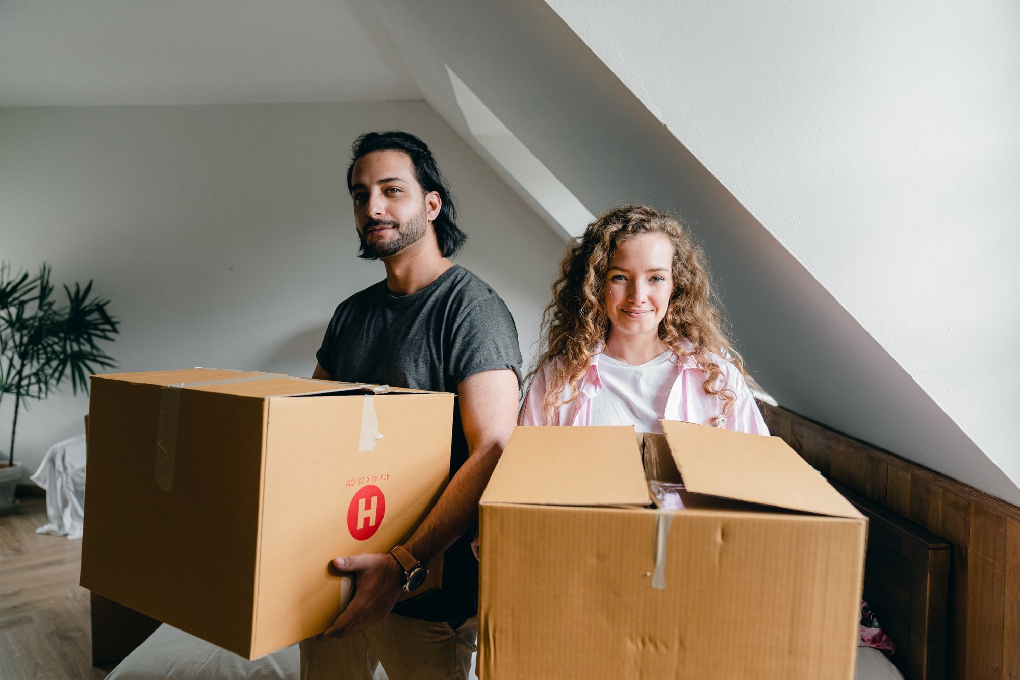 Couple holding moving boxes in their new home