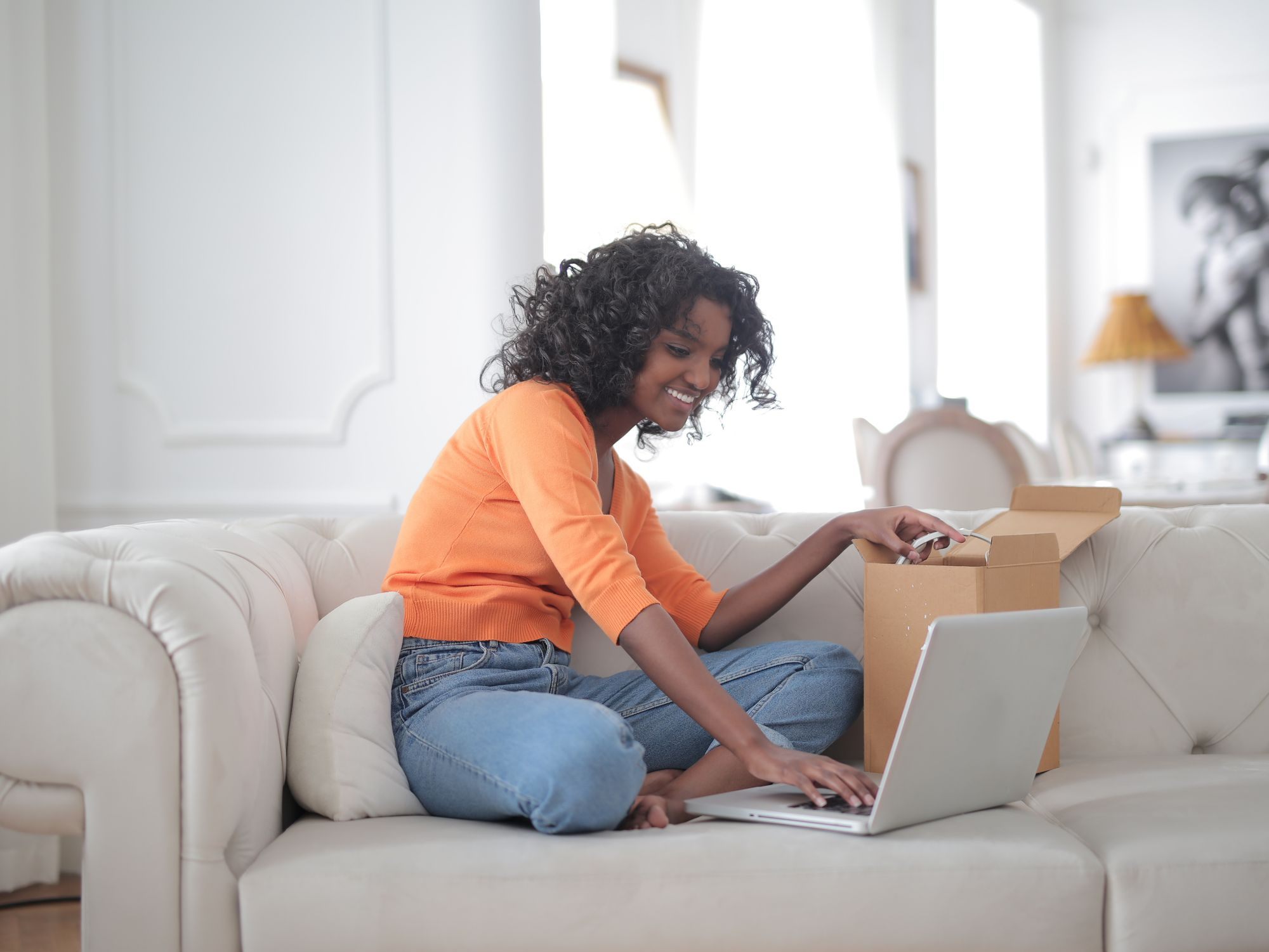 Woman on a sofa using a laptop in a bright living room