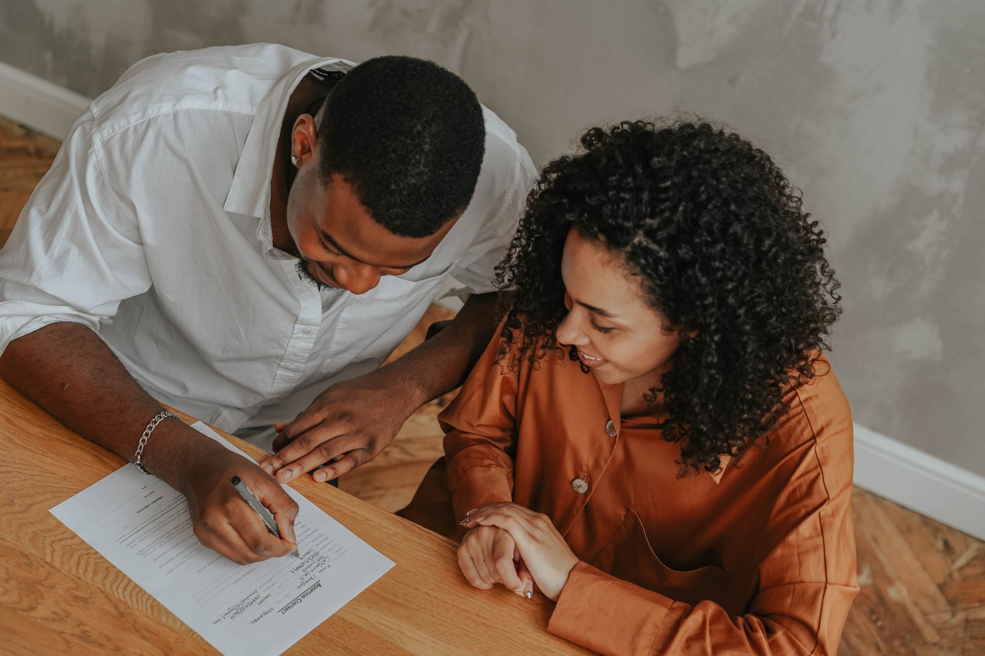 Couple signing documents at a dining table