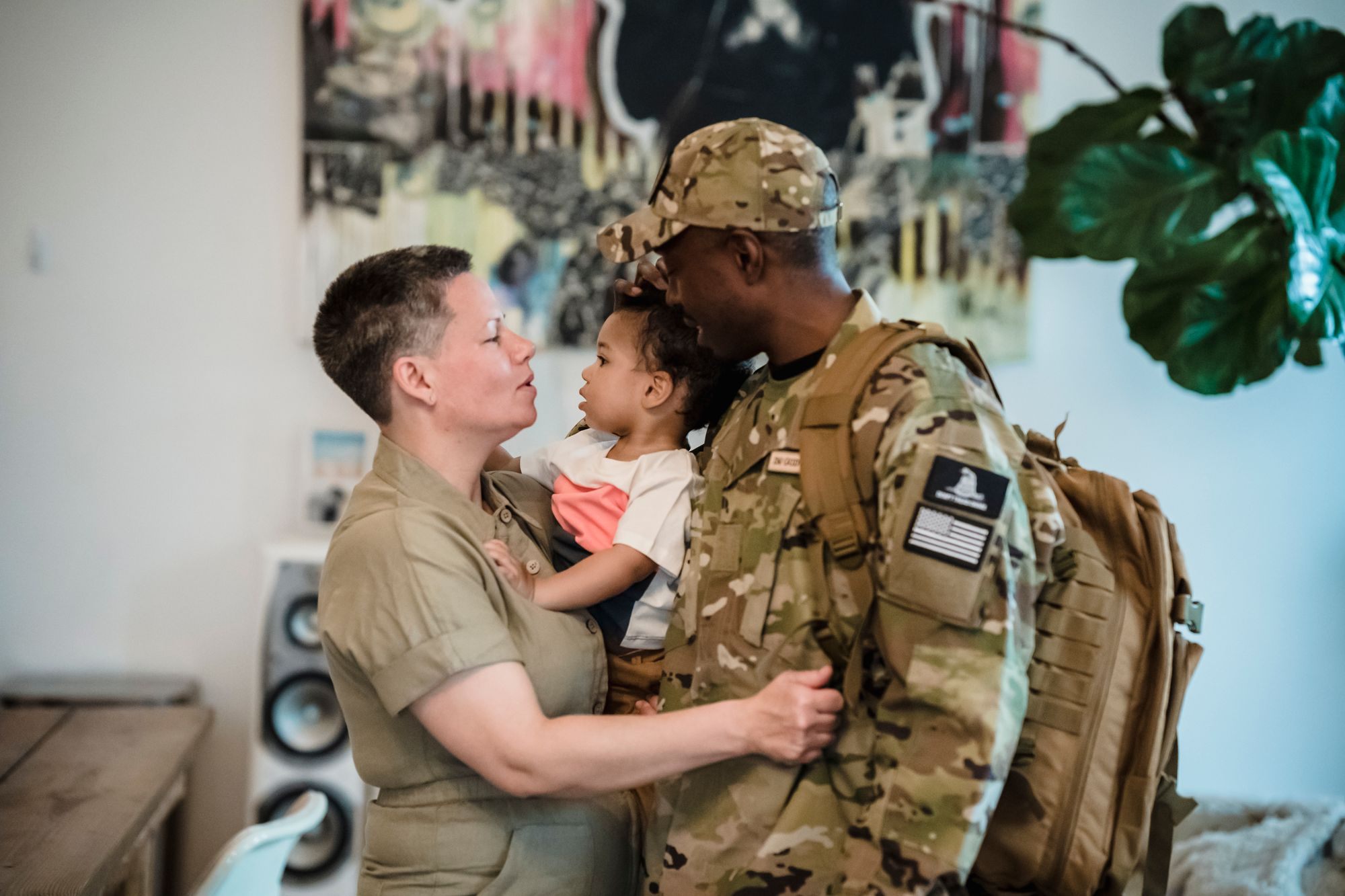 Soldier home from deployment embracing their partner and child