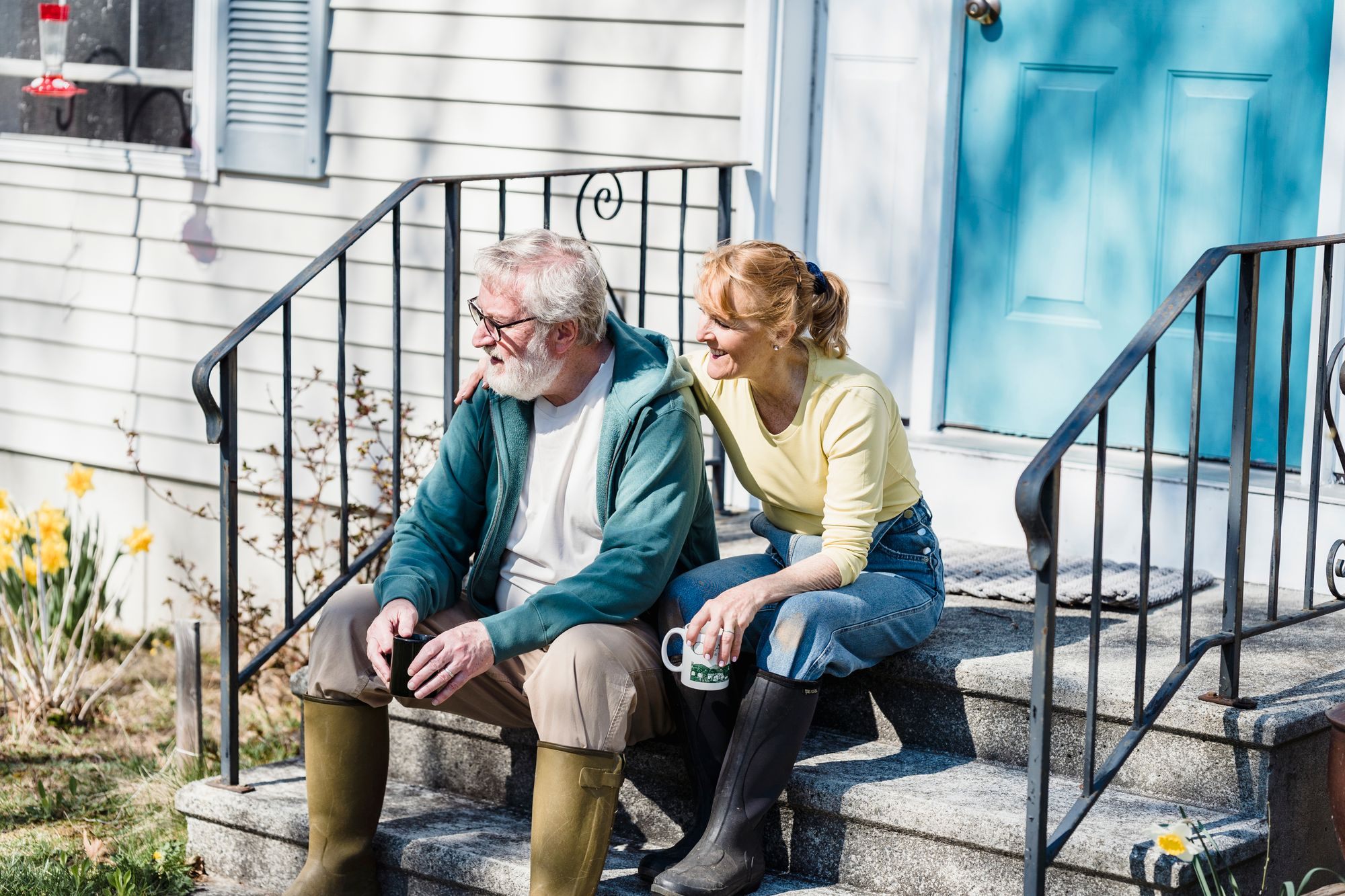 Couple sitting on the front steps of their home with coffee